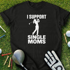 Black t-shirt with "I support single moms" text and golfer graphic on green grass.