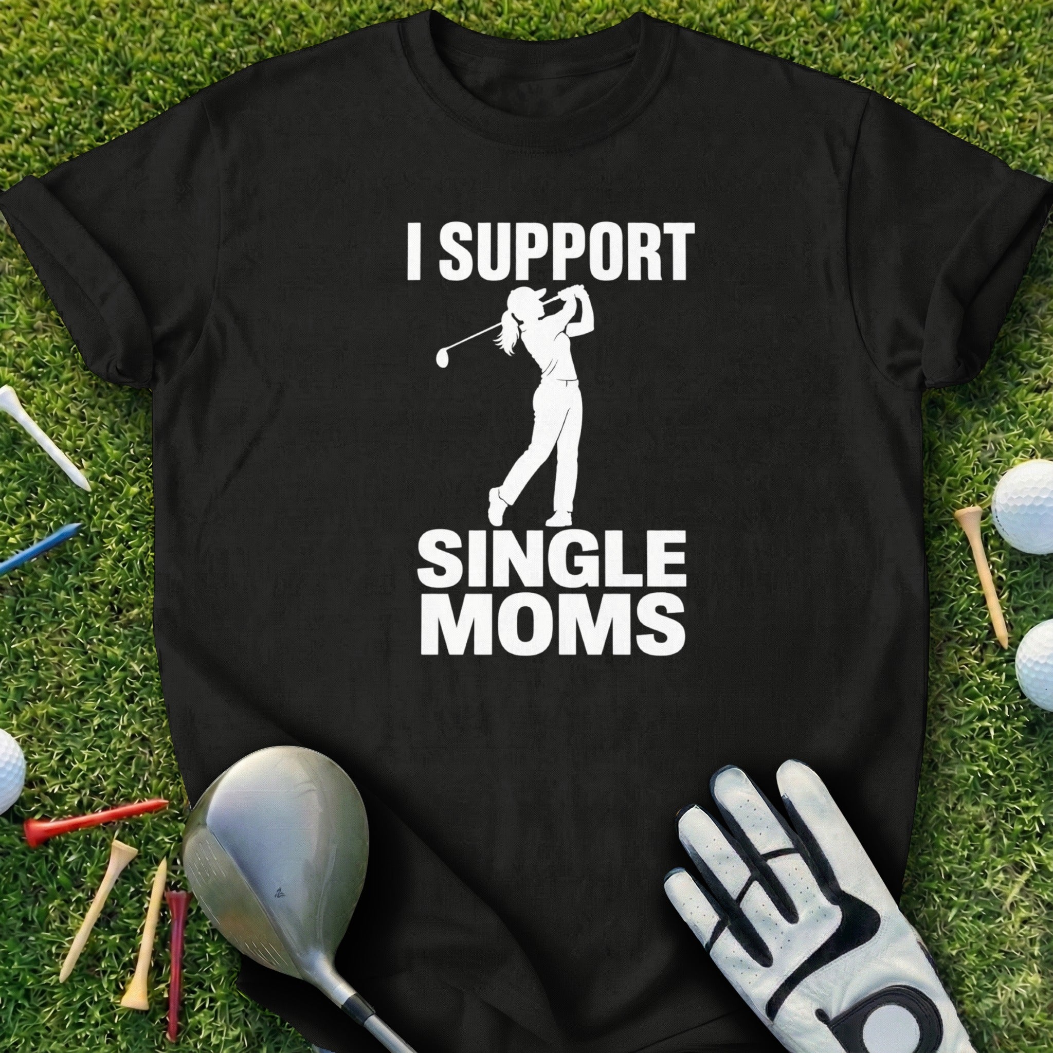 Black t-shirt with "I support single moms" text and golfer graphic on green grass.