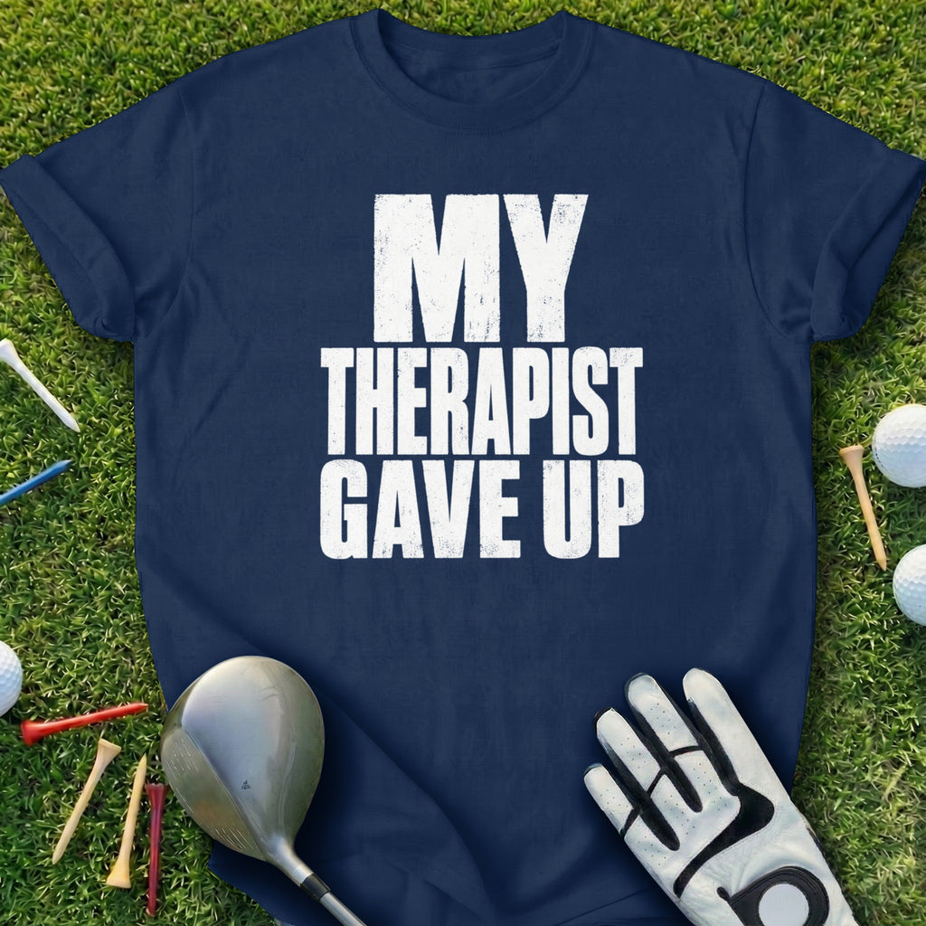 Navy t-shirt with white text reading "MY THERAPIST GAVE UP" on grass with golf equipment.
