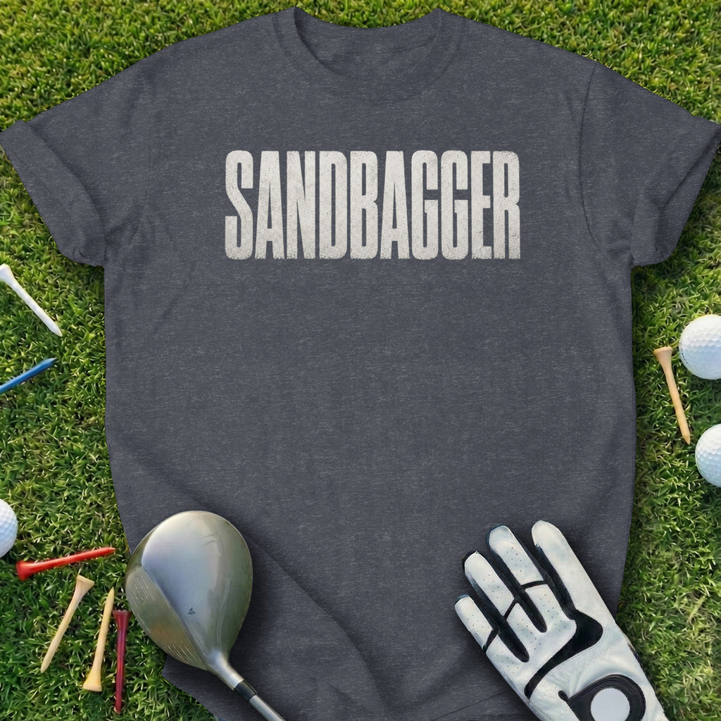 Dark grey t-shirt with "SANDBAGGER" in white distressed lettering on grass.
