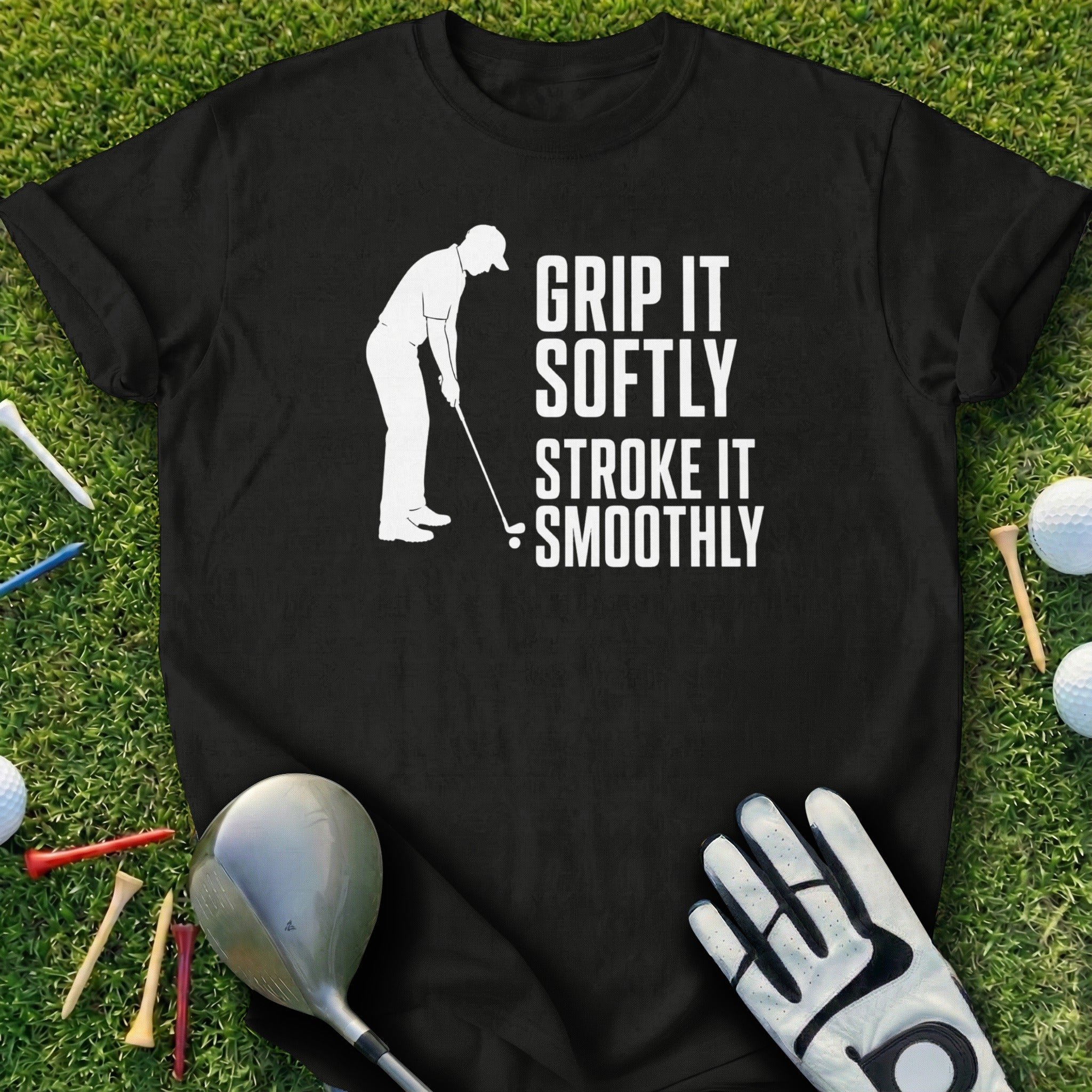 Black t-shirt with white text "Grip it softly, stroke it smoothly" on a golf course.