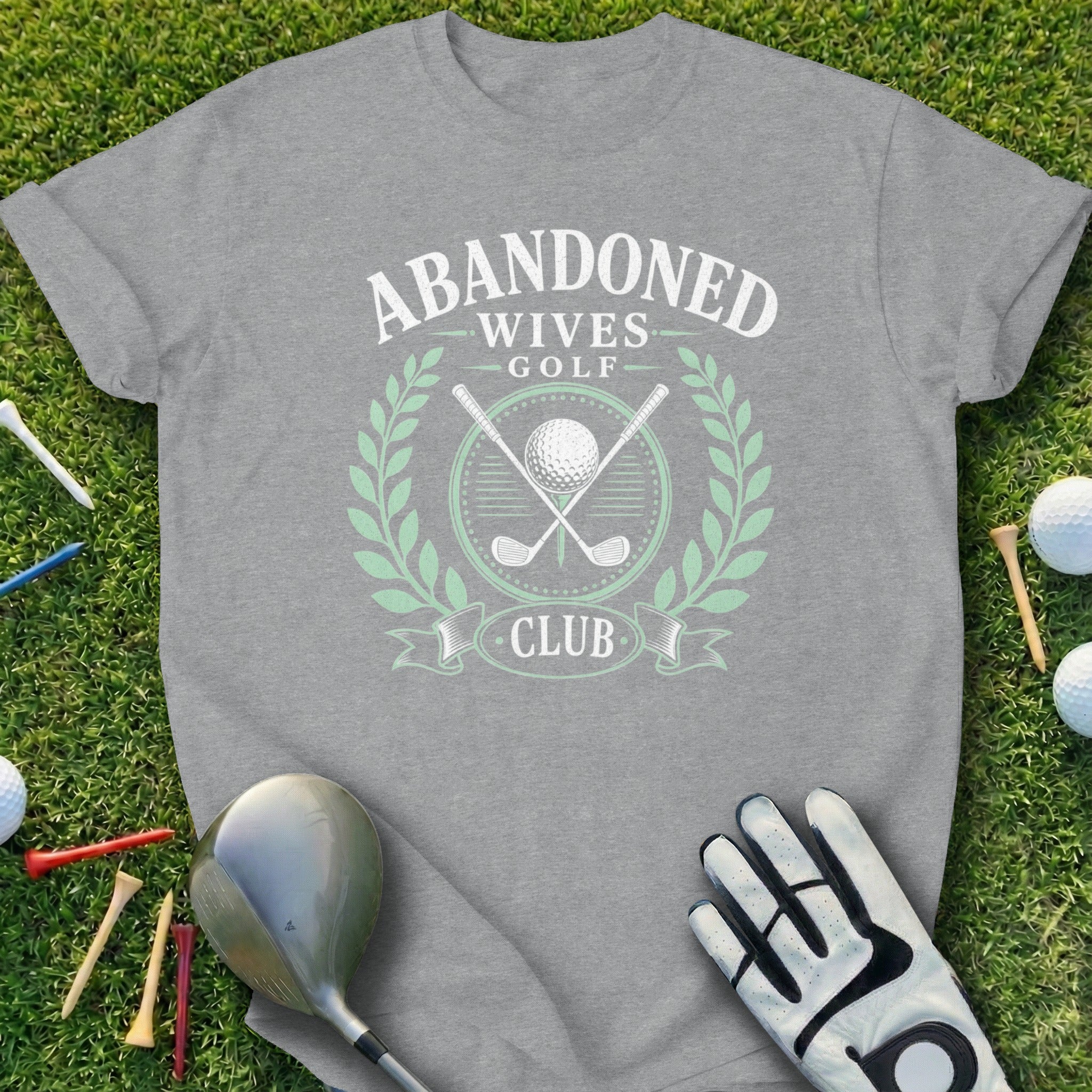 Gray t-shirt with "Abandoned Wives Golf Club" logo on grass.