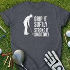 Dark grey t-shirt with white text "GRIP IT SOFTLY STROKE IT SMOOTHLY" and a golfer silhouette.