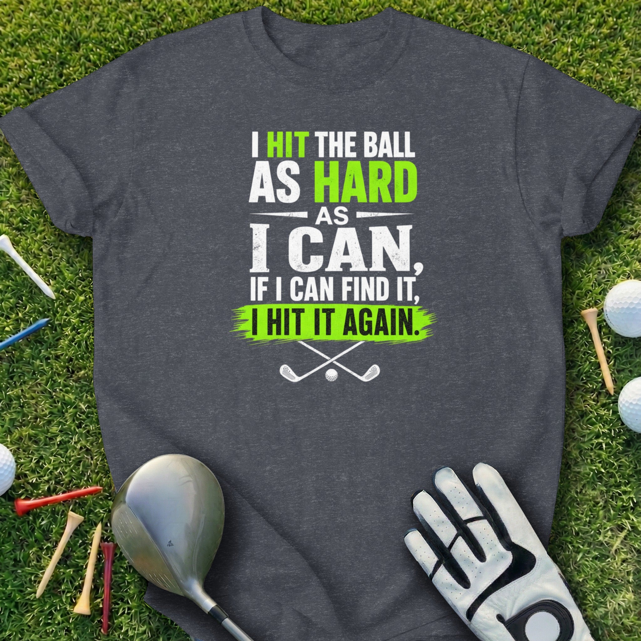 Dark grey t-shirt with golf-themed text: "I HIT THE BALL AS HARD AS I CAN, IF I CAN FIND IT, I HIT IT AGAIN."