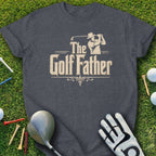 Dark grey t-shirt with "The Golf Father" text and golf accessories on grass.