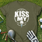 Olive green t-shirt with "KISS MY" golf ball design on grass with clubs and tees.