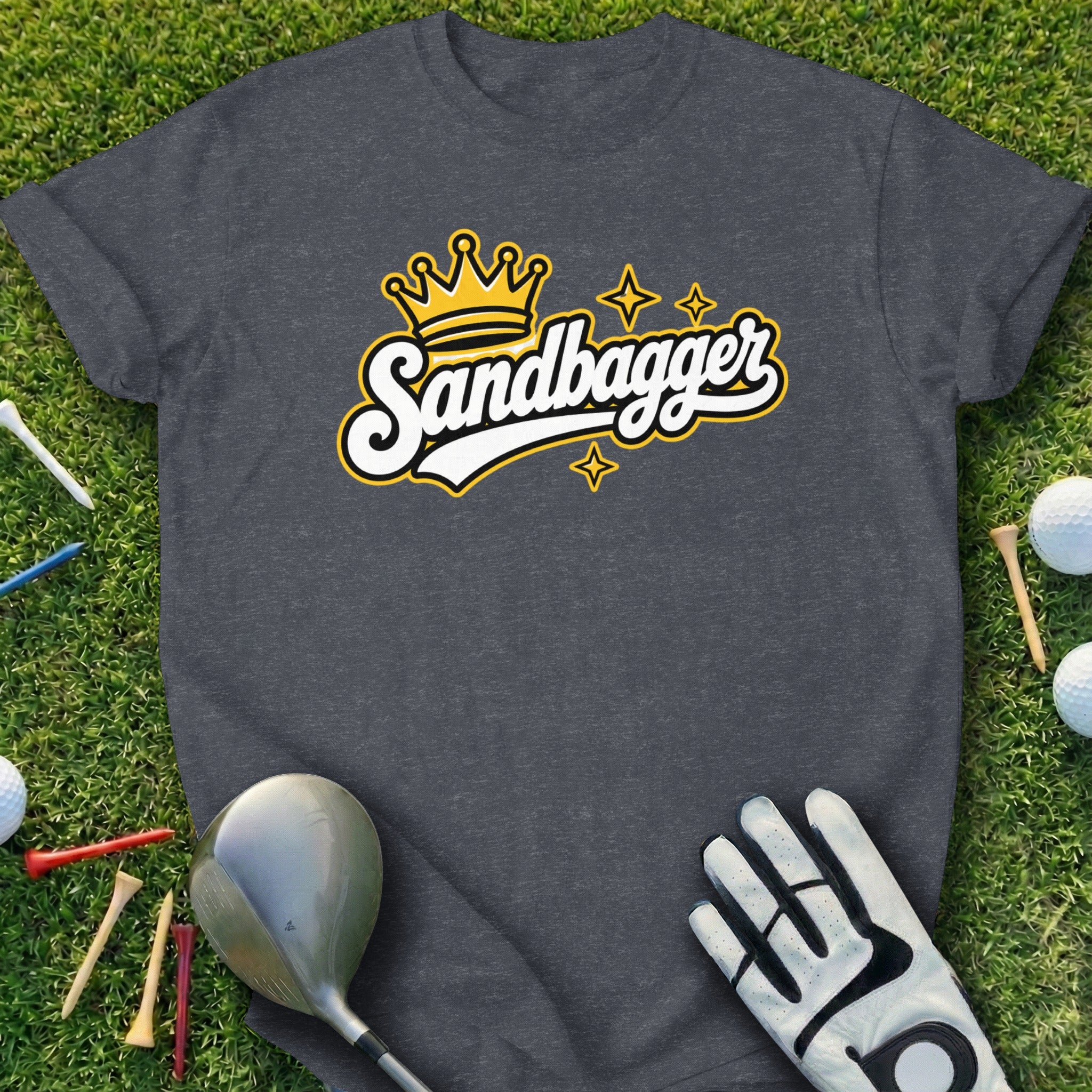 Dark gray t-shirt with "Sandbagger" logo and golf accessories on grass.