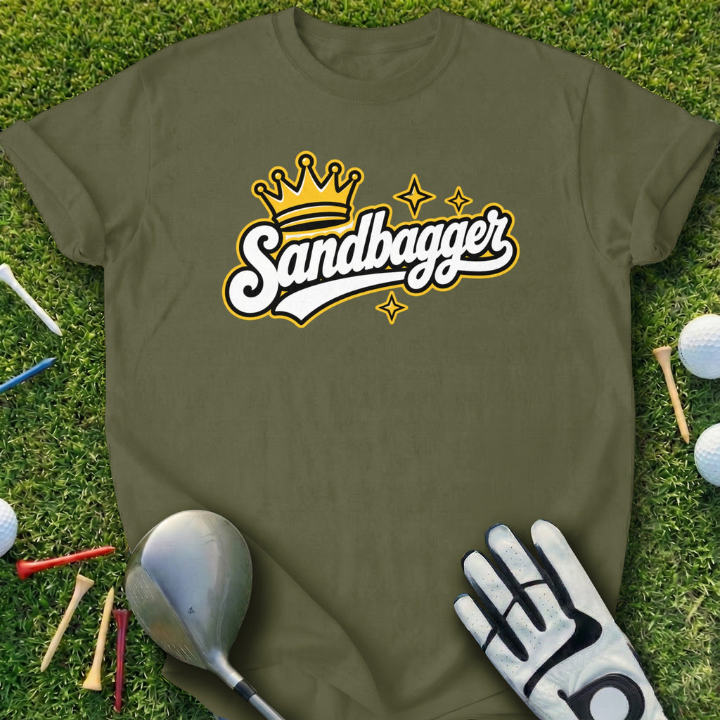 Green t-shirt with "Sandbagger" text and a crown graphic, on grass with golf clubs and balls.