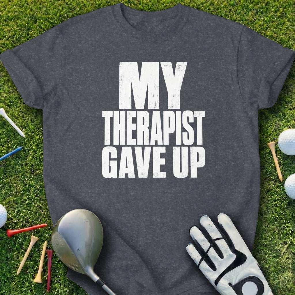 Dark grey t-shirt with "MY THERAPIST GAVE UP" text, golf club, glove, and tees.