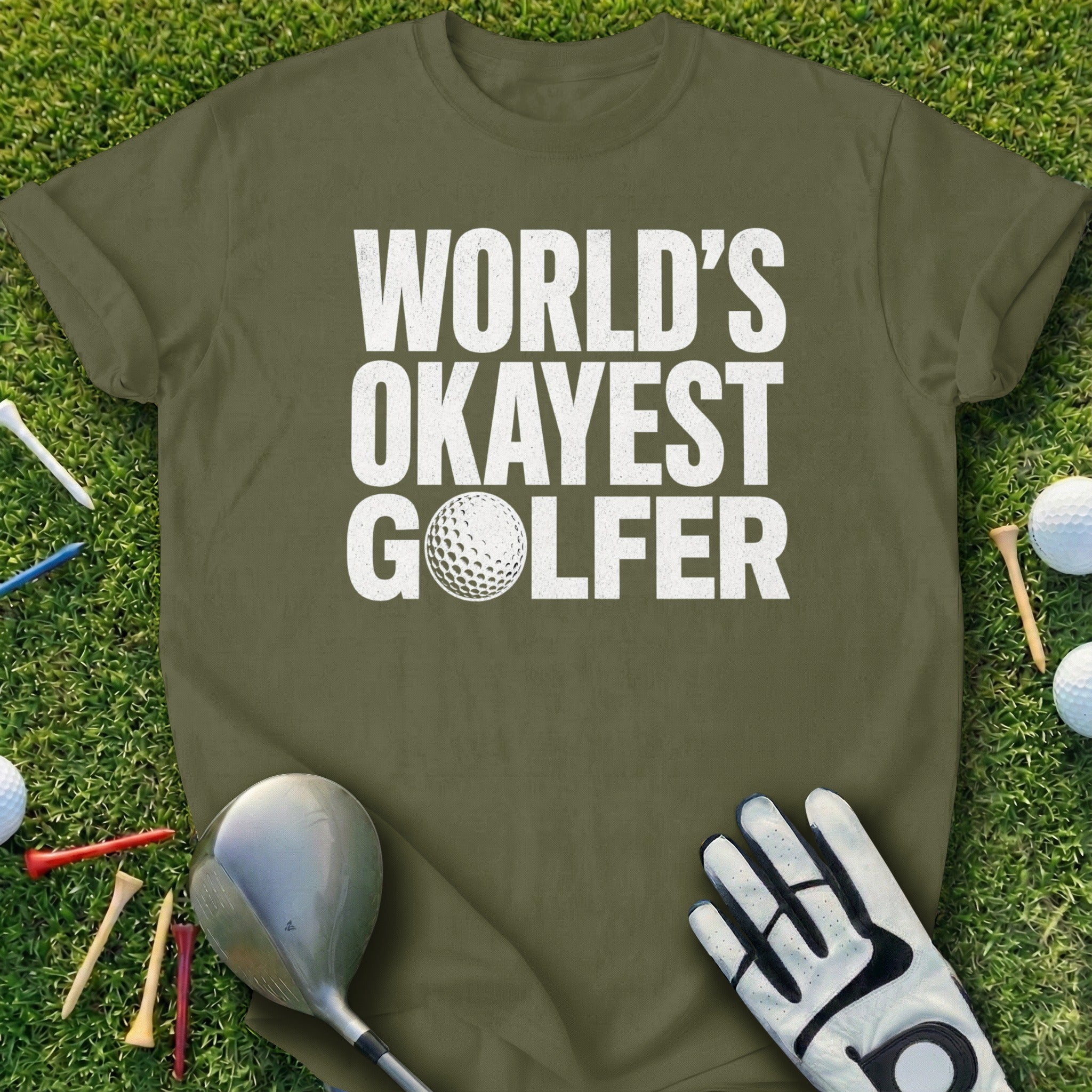 Green t-shirt with white text "WORLD'S OKAYEST GOLFER" and golf accessories.