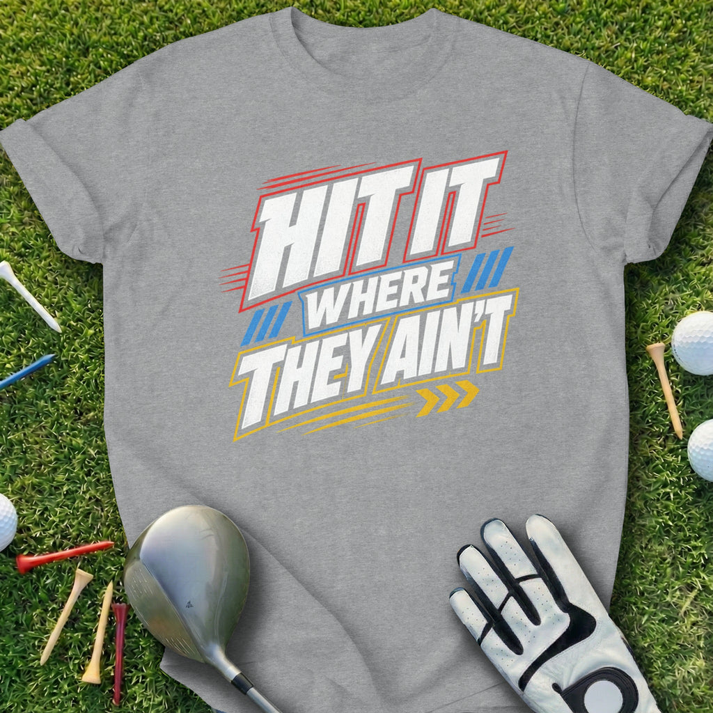 Gray t-shirt with "HIT IT WHERE THEY AIN'T" text, golf glove, tees, and balls on grass.