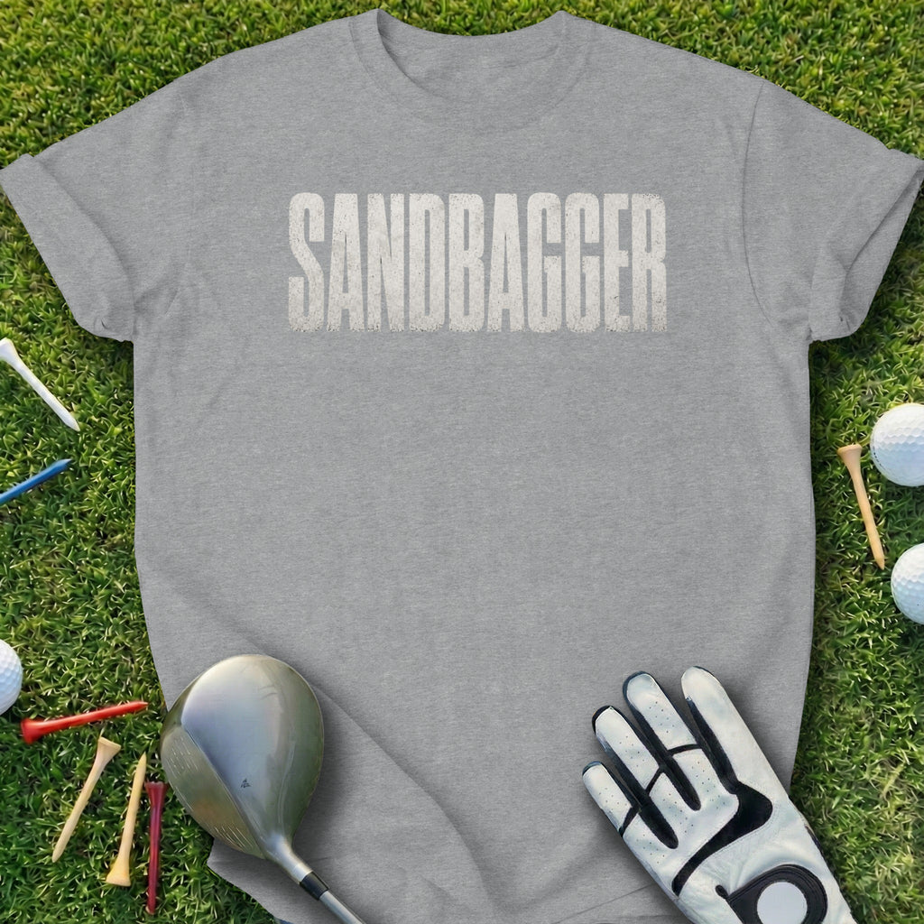Gray t-shirt with "SANDBagger" text and golf accessories on grass.